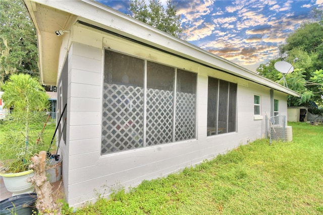 property exterior at dusk featuring a yard