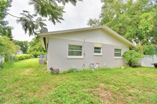 view of side of property featuring central air condition unit and a yard