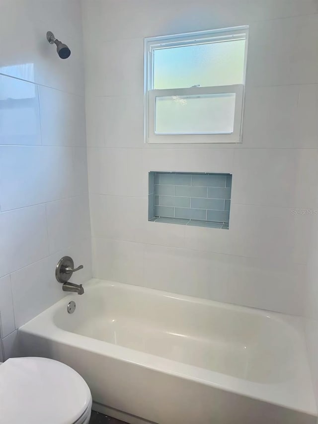 bathroom with toilet, tile walls, and tiled shower / bath