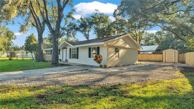 view of front of property featuring a patio, a storage shed, and a front lawn