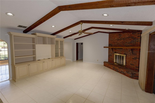 unfurnished living room with ceiling fan, lofted ceiling with beams, a textured ceiling, and a fireplace