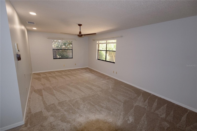 carpeted spare room featuring ceiling fan and a textured ceiling