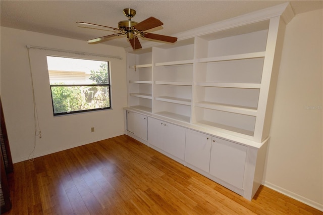 spare room featuring light hardwood / wood-style flooring, ceiling fan, built in features, and a textured ceiling