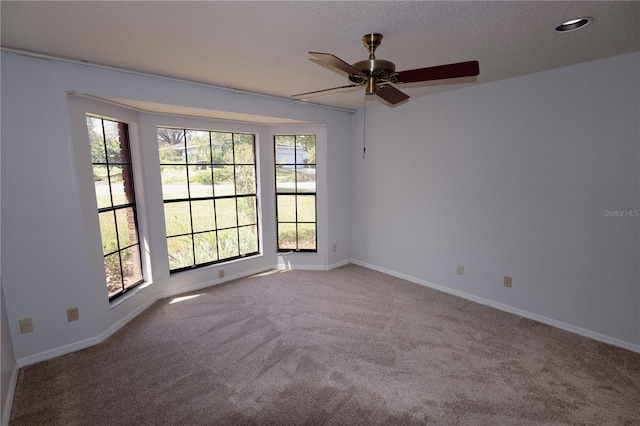 carpeted spare room with a textured ceiling and ceiling fan