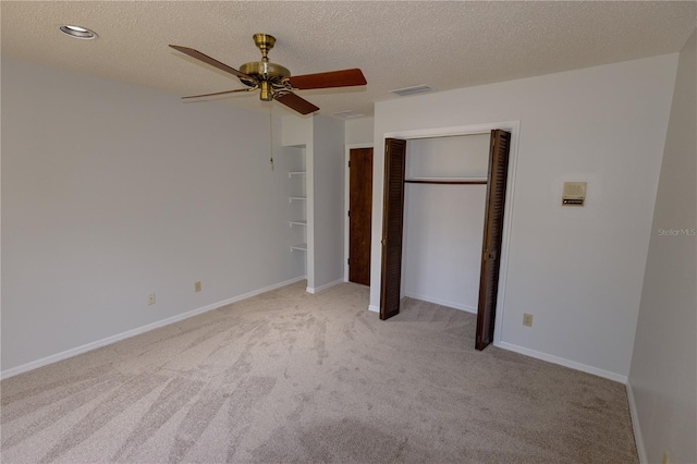 unfurnished bedroom featuring ceiling fan, light carpet, a textured ceiling, and a closet