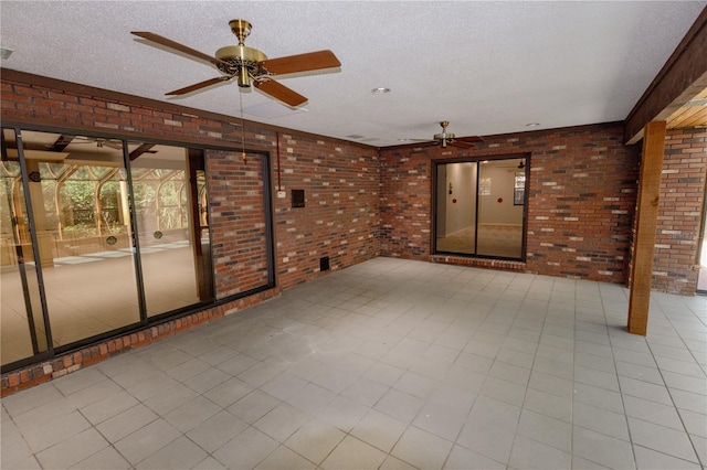 interior space with ceiling fan, brick wall, and a textured ceiling