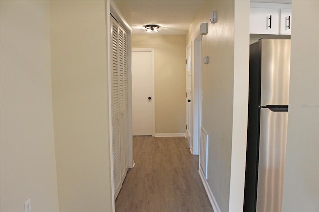 hall with a textured ceiling and wood-type flooring