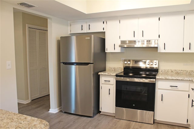 kitchen with stainless steel appliances, baseboards, light wood-type flooring, under cabinet range hood, and visible vents