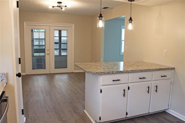 kitchen with dark wood-style flooring, visible vents, baseboards, a peninsula, and white cabinetry