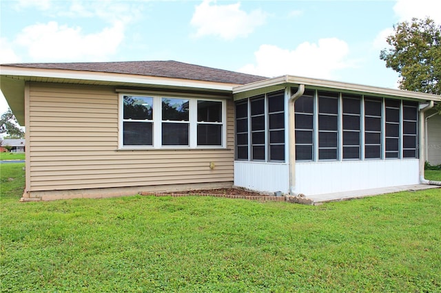 back of house with a yard, a shingled roof, and a sunroom