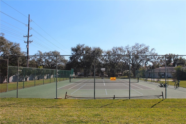 view of tennis court featuring fence and a yard