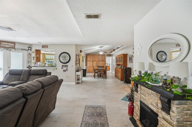 living room with french doors, a textured ceiling, a stone fireplace, and ceiling fan