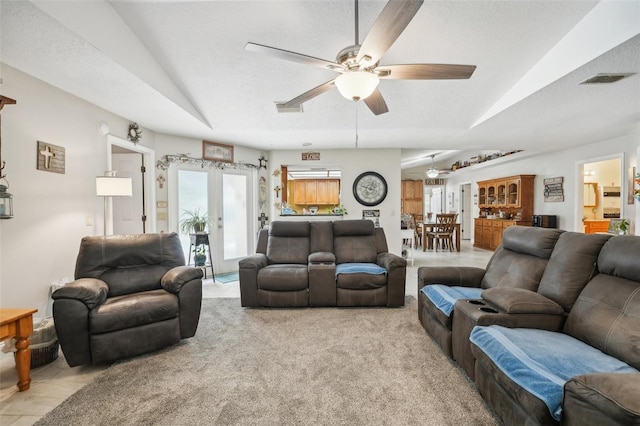 carpeted living room with ceiling fan, french doors, and a textured ceiling