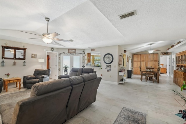 living room featuring a textured ceiling, vaulted ceiling, and ceiling fan