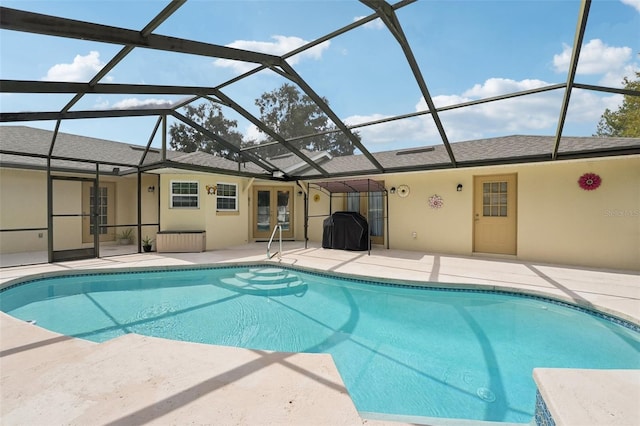 view of pool featuring glass enclosure, a patio, and french doors