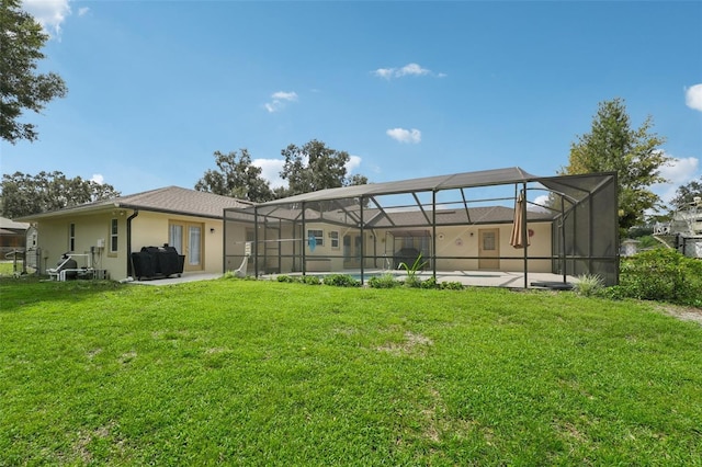 rear view of property featuring a lawn and glass enclosure