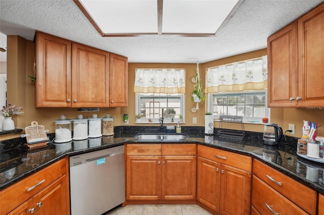 kitchen with stainless steel dishwasher, dark stone countertops, sink, and a textured ceiling