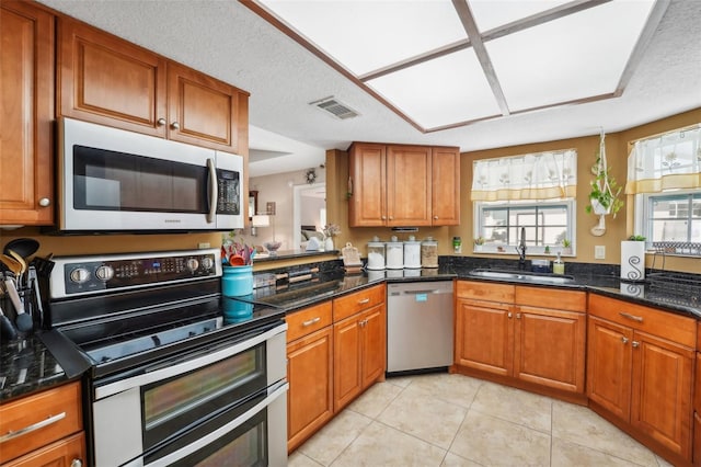 kitchen featuring a textured ceiling, dark stone countertops, sink, and appliances with stainless steel finishes