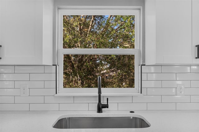 room details featuring light stone countertops, white cabinetry, sink, and tasteful backsplash