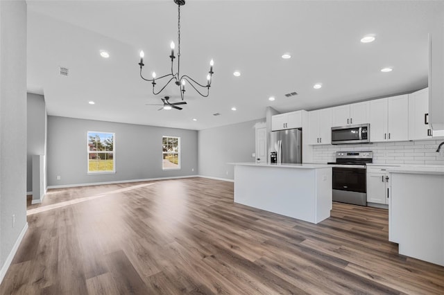 kitchen with white cabinets, a center island, stainless steel appliances, and dark hardwood / wood-style floors