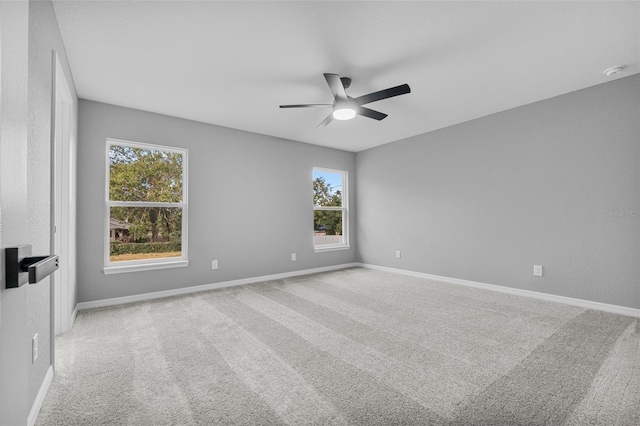 spare room with ceiling fan, light carpet, and a wealth of natural light