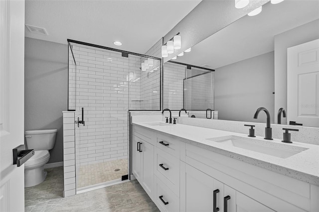 bathroom featuring a shower with door, vanity, and toilet