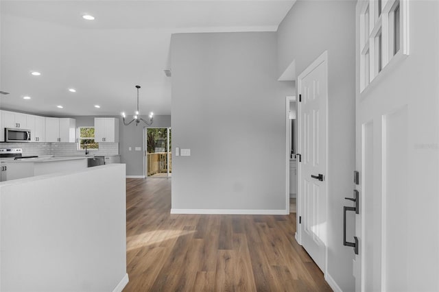 kitchen featuring hanging light fixtures, stainless steel appliances, dark hardwood / wood-style flooring, decorative backsplash, and white cabinets