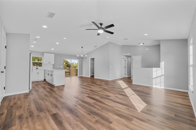 unfurnished living room with ceiling fan with notable chandelier, hardwood / wood-style flooring, lofted ceiling, and sink