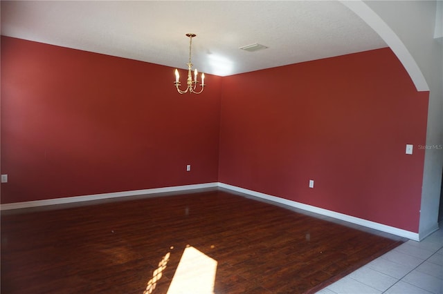 unfurnished room with a textured ceiling, hardwood / wood-style floors, and a notable chandelier