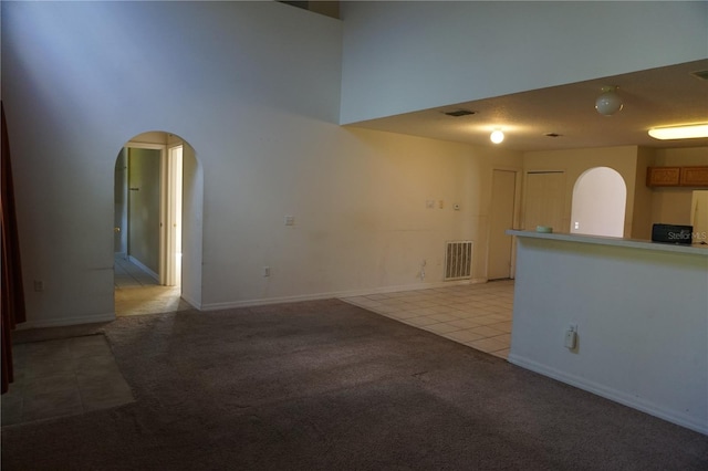 interior space with light carpet and a towering ceiling