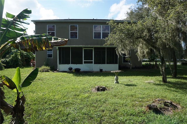 rear view of house featuring a sunroom and a lawn