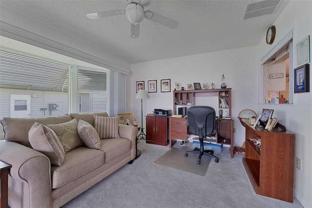 carpeted office space with ceiling fan and a textured ceiling