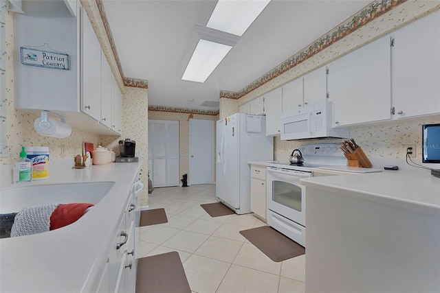 kitchen with white cabinets, white appliances, light tile patterned floors, and sink