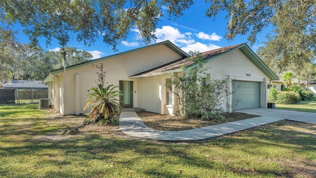 view of front of house with central air condition unit, a front lawn, and a garage