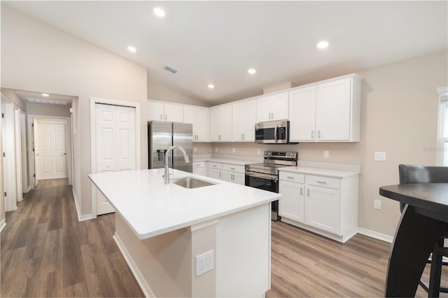 kitchen with visible vents, a sink, white cabinetry, stainless steel appliances, and lofted ceiling