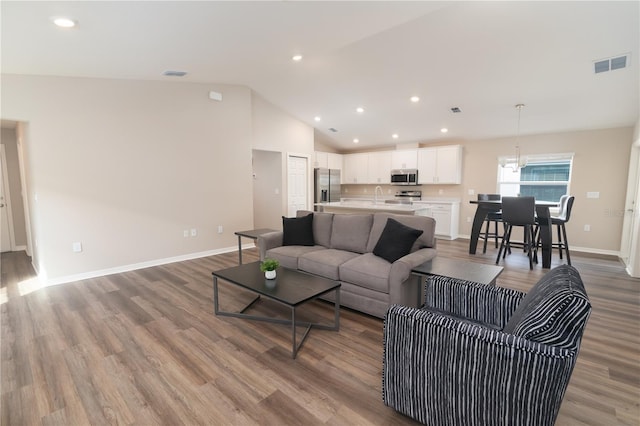 living area with lofted ceiling, light wood-style floors, visible vents, and baseboards