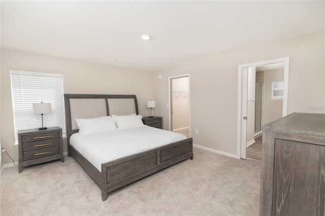 bedroom featuring a spacious closet, baseboards, a closet, and light carpet