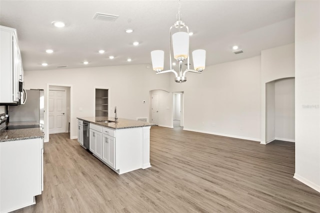 kitchen featuring sink, white cabinetry, hanging light fixtures, an island with sink, and dark stone counters