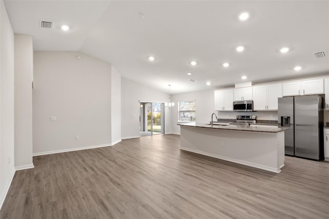 kitchen featuring sink, white cabinetry, a center island with sink, dark stone countertops, and stainless steel appliances