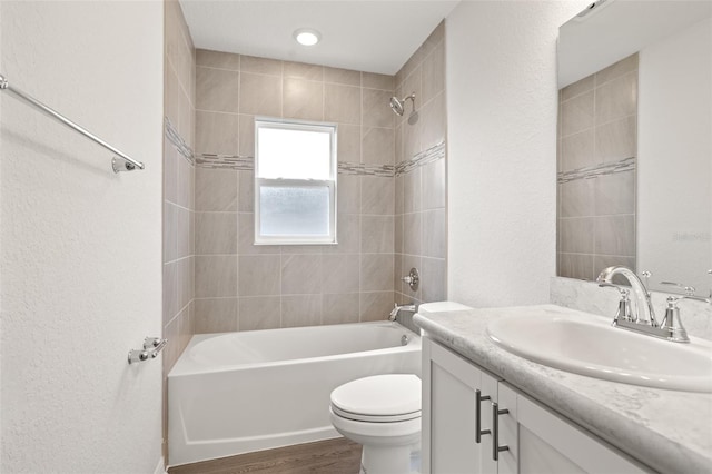 full bathroom featuring tiled shower / bath combo, vanity, hardwood / wood-style floors, and toilet