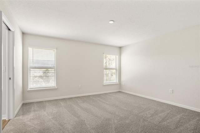 empty room with light carpet and a textured ceiling