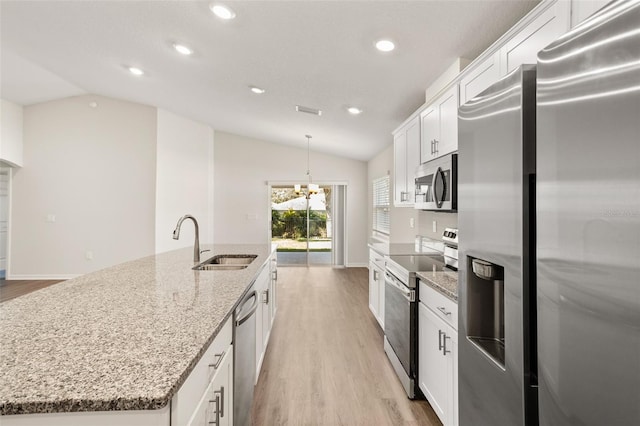 kitchen featuring lofted ceiling, sink, appliances with stainless steel finishes, white cabinets, and a center island with sink