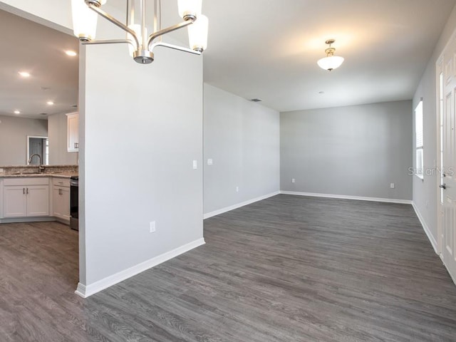 unfurnished room with sink, dark wood-type flooring, and an inviting chandelier