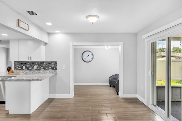 kitchen featuring light hardwood / wood-style flooring, white cabinets, light stone counters, and tasteful backsplash