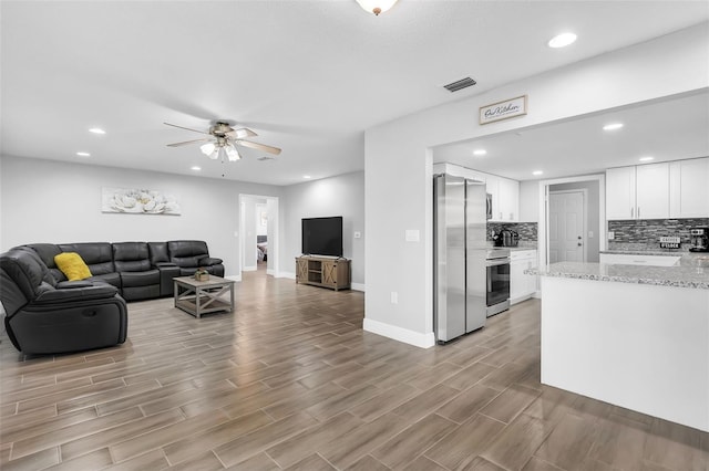 living room with ceiling fan and light hardwood / wood-style flooring