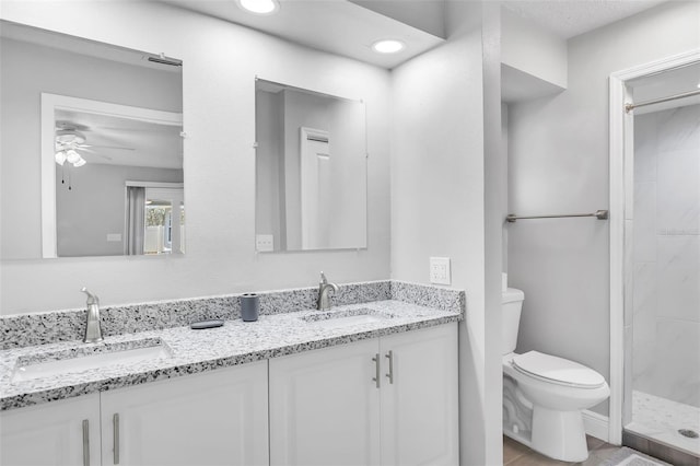 bathroom with vanity, a shower, toilet, and ceiling fan