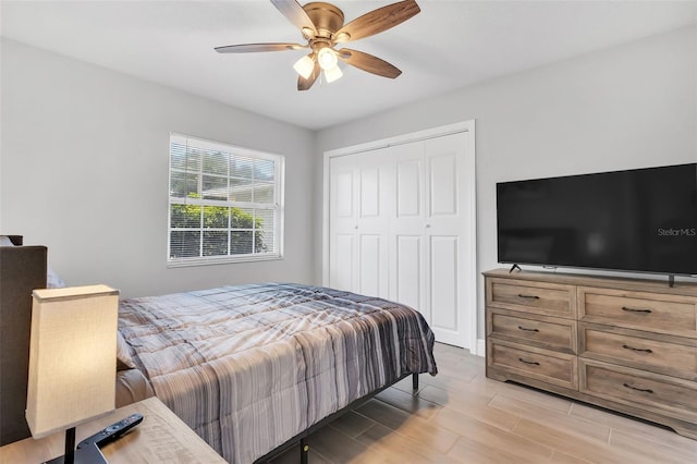 bedroom with light wood-type flooring, ceiling fan, and a closet