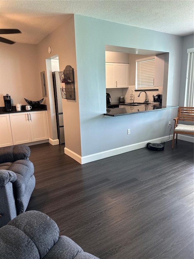 living room featuring ceiling fan, a textured ceiling, dark hardwood / wood-style floors, and sink