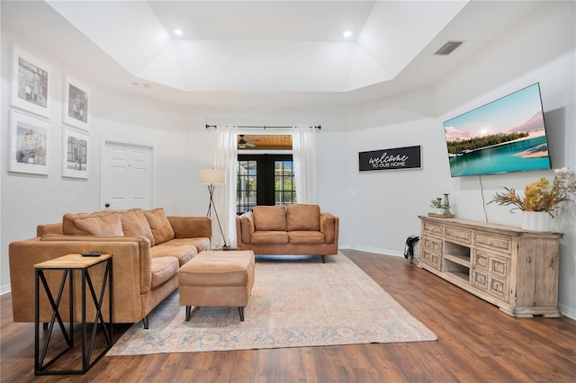 living room with dark hardwood / wood-style flooring, french doors, a raised ceiling, and a high ceiling