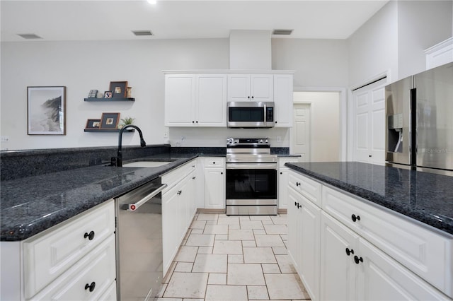 kitchen featuring stainless steel appliances, sink, white cabinets, and dark stone counters